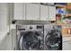 Modern laundry room featuring front loading washer and dryer with white cabinets at 4678 San Benito St, Las Vegas, NV 89121