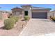 Inviting single-story home with a stone facade, desert landscaping and a paver driveway leading to a two-car garage at 5555 E San Pietro Dr, Pahrump, NV 89061