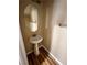 Well-lit half bath with a pedestal sink, oval mirror, and modern fixtures, complemented by wood-look flooring at 566 Shewsbury Ave, Las Vegas, NV 89178