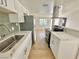 Open-concept kitchen with stainless steel appliances, white cabinets, and laminate flooring at 604 N Minnesota St, Las Vegas, NV 89107