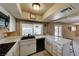 Well-lit kitchen featuring white cabinetry, tiled countertops, black appliances, and a garden window at 637 Del Prado Dr, Boulder City, NV 89005