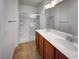 Well-lit bathroom with double sinks, wood cabinets, and a glass-enclosed shower at 7024 Whispering Falls Dr, North Las Vegas, NV 89084