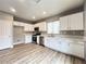 Well-lit kitchen features stainless appliances, white cabinetry, and wood-look flooring at 7696 Mocorito Ave, Las Vegas, NV 89113