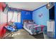 Vibrant bedroom with blue walls, a single bed, colorful decor, and natural light at 7820 Esteem St, Las Vegas, NV 89131