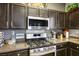 Close up of stainless steel stove and microwave with dark wood cabinetry and quartz countertops at 7820 Esteem St, Las Vegas, NV 89131