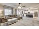 Open-concept living room featuring tile floors, ceiling fan, and a gray sectional sofa with throw pillows at 7828 Stone Forest St, North Las Vegas, NV 89084