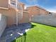 Fully fenced backyard with faux grass and a tiled stone patio area at 8032 Astrology Ct # 201, Las Vegas, NV 89128
