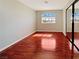 Well-lit bedroom featuring wood floors, a window with natural light, and mirrored closet doors at 8032 Astrology Ct # 201, Las Vegas, NV 89128