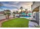 Serene backyard oasis featuring a lush lawn, sparkling pool, mature palm trees, and a charming patio area at 8032 Marbella Cir, Las Vegas, NV 89128