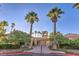 Welcoming community entrance with lush landscaping, palm trees, and a charming building at 8032 Marbella Cir, Las Vegas, NV 89128