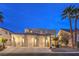 Charming two-story stucco home featuring a three-car garage and desert landscaping at twilight at 8032 Marbella Cir, Las Vegas, NV 89128