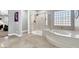 Bright bathroom featuring a glass-enclosed shower and luxurious soaking tub with tile surround and decorative glass block window at 8102 Villa De La Playa St, Las Vegas, NV 89131