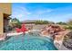 Gorgeous swimming pool featuring rock waterfall, adjacent hot tub, and surrounding patio seating for outdoor enjoyment at 8102 Villa De La Playa St, Las Vegas, NV 89131