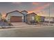 Charming single-story home featuring desert landscaping, brick driveway, and a stone-accented facade at sunset at 827 Klamath Springs St, Henderson, NV 89011