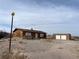 Rustic wooden home with boarded-up windows, situated on a gravel lot under a cloudy sky at 895 Greasewood Ln, Moapa, NV 89025