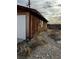 Side view of a dilapidated wooden building with overgrown vegetation and a rugged terrain at 895 Greasewood Ln, Moapa, NV 89025