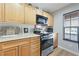 Kitchen featuring wood cabinets, an oven, a microwave, and a window for natural light at 9053 Pearl Cotton Ave, Las Vegas, NV 89149