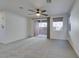 Bright living room featuring plush carpeting, a ceiling fan, and sliding door access to the backyard at 10581 Griffin Ave, Las Vegas, NV 89129