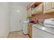 Bright laundry room includes wood cabinets, tile floor, sink, and front-loading washer and dryer at 1093 Morning Sun Way, Las Vegas, NV 89110