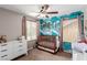 Bedroom with a crib, changing table, dresser, ceiling fan and an accent wall with a cool ocean pattern at 11237 Gallery Echo St, Las Vegas, NV 89141