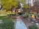 Landscaped walkway through a park with mature trees, bushes, park bench, and green grass at 11820 Calle De Sol Dr, Las Vegas, NV 89138