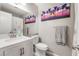 Well-lit bathroom featuring a single sink vanity, toilet, and a framed mirror with palm tree art at 212 N Torrey Pines Dr, Las Vegas, NV 89107