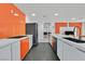 Well-designed kitchen with white and orange cabinetry, stainless steel appliances, and a view into the living spaces at 2221 Mohawk St, Las Vegas, NV 89146