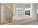 Bright bathroom featuring a glass shower, soaking tub with fireplace, and a window with palm tree views at 4679 El Camino Cabos Dr, Las Vegas, NV 89147