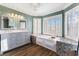 Bathroom with a soaking tub and a large, marble-topped vanity, bathed in natural light at 5 Rampart Ct, Henderson, NV 89074