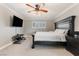 Bedroom with a dark wood bed frame, mounted television, ceiling fan, and plantation shutters at 5 Rampart Ct, Henderson, NV 89074