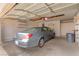 Attached garage with a parked sedan, overhead storage, and a trash bin at 5033 Chambliss Dr, Las Vegas, NV 89130