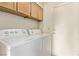 Bright laundry room with washer, dryer, overhead storage cabinets and a white door at 5033 Chambliss Dr, Las Vegas, NV 89130