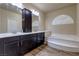 Bathroom with dual vanities, dark wood cabinets, and separate tub with marble surround at 6403 Brandon Hills Ct, Las Vegas, NV 89139