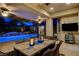 Covered outdoor patio with a dining table setting next to a luminous pool at 9475 Windham Heights Ct, Las Vegas, NV 89139