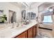 Bright bathroom featuring double sinks, wood cabinets, and a view into the connected bedroom at 10086 Aspen Rose St # 101, Las Vegas, NV 89183