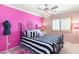 Stylish bedroom with pink walls, striped bedding, chandelier and ample lighting at 10892 Royal Highlands St, Las Vegas, NV 89141
