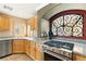 Updated kitchen features granite countertops, stainless appliances, a decorative window, and natural wood cabinetry at 10892 Royal Highlands St, Las Vegas, NV 89141