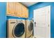 Laundry room boasts side-by-side washer and dryer with overhead cabinet storage and vibrant blue walls at 10892 Royal Highlands St, Las Vegas, NV 89141