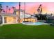 Lush backyard with swimming pool, spa, manicured lawn, and a beautiful sunset at 2221 Glenbrook Way, Las Vegas, NV 89117