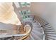 Sweeping spiral staircase with ornamental metal handrail and a view of the upper floor chandelier and windows at 2221 Glenbrook Way, Las Vegas, NV 89117