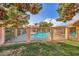 Community pool surrounded by wrought iron fence, lush greenery and a pergola for relaxation and shaded seating at 2611 Laguna Shores Ln, Las Vegas, NV 89121