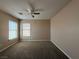 Spacious bedroom with two windows allowing natural light, neutral walls and carpeting, and a ceiling fan at 2628 Park Hyatt Ave, North Las Vegas, NV 89081