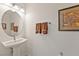 This bathroom features a pedestal sink with an oval mirror and decorative artwork at 5450 Barnwood Ct, Pahrump, NV 89061