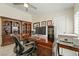 Home office with a desk, computer, large windows, bookshelves, and comfortable seating at 5450 Barnwood Ct, Pahrump, NV 89061