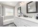 Bathroom showcasing a double vanity with quartz countertops and modern fixtures plus a tub and window at 5552 Singing Hills Dr, Las Vegas, NV 89130