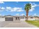 Charming single-story home featuring a spacious driveway, a garage, and a large palm tree at 7060 S Valley View Blvd, Las Vegas, NV 89118