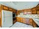 Vintage kitchen with wood cabinets, white appliances, and floral wallpaper at 7079 Laredo St, Las Vegas, NV 89117