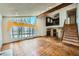 Bright living room with wood floors, large window with vintage curtains, and wooden staircase at 7079 Laredo St, Las Vegas, NV 89117