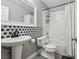 Bathroom featuring a pedestal sink with hexagon backsplash, a toilet, and a shower-tub combo at 7621 Gosport Ave, Las Vegas, NV 89131