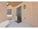Close up of the home's black, decorative security door, and tan exterior with a welcome mat and front light fixture at 7621 Gosport Ave, Las Vegas, NV 89131
